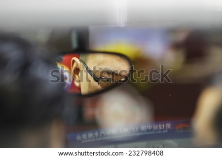 GUANGZHOU, CHINA - NOV. 20. 2014: Man seen in review mirror seating in car on the 12th China International Automobile Exhibition in Guangzhou, Guangdong province.