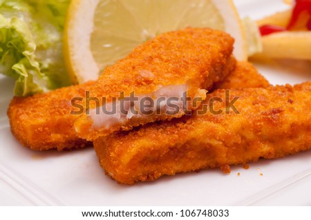 Fast food with three breaded fish fingers and a slice of lemon