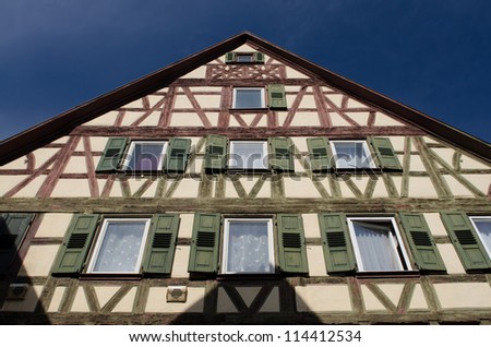 Half timbered house with green and red timbers and a blue sky