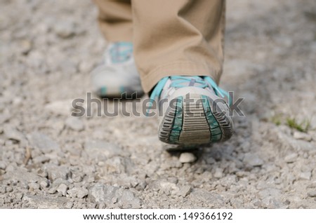 Close up of two feet with shoes are hiking on a stony way