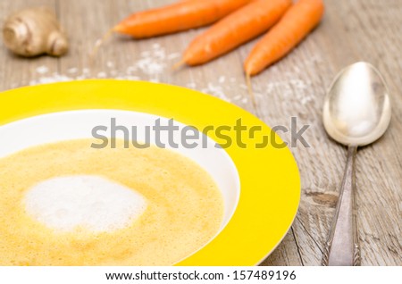 Carrot soup with foam of coconut milk on a wooden table