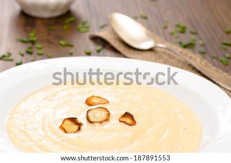 Parsnips soup with roasted parsnips in a white porcelain plate