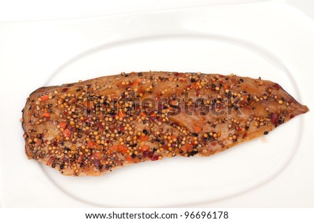 Smoked mackerel with peppercorns and mustard seeds on a white plate