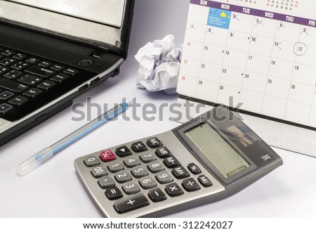 calculator and pen and notebook computer on work table