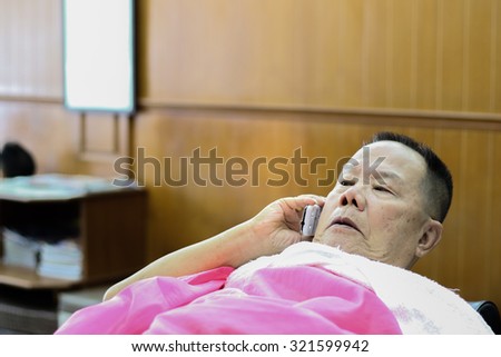 The old man Asia Thai sleeping talk phone in the barber shop