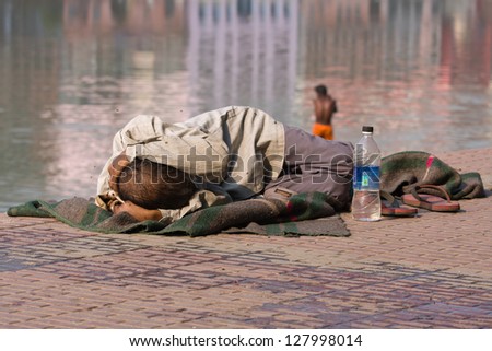 HARIDWAR, INDIA - NOV 8: An unidentified homeless man sleeps on the sidewalk near the River Ganges on November 8, 2012 in Haridwar, India. Poor Indians flock to Haridwar for charity.