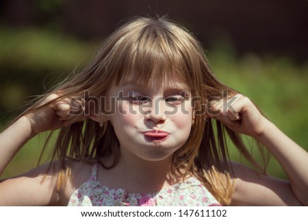 Portrait cross-eyed young girl on the nature in summer day