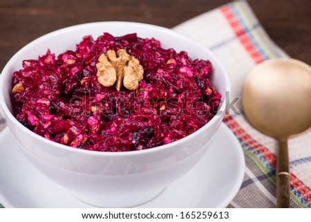 Fresh salad with beet and walnuts on white plate