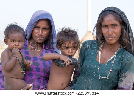 PUSHKAR, INDIA - OCTOBER 23 2014: An unidentified beggar women and children beg for money from a passerby in Pushkar. Poverty is a major issue in India