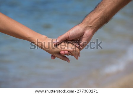 Couple hands against the sea view, close up