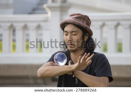 BANGKOK , THAILAND - JANUARY 22, 2015: Unknown street performer juggling glass bowl in front of passers-by on the street Khao San Road in Bangkok