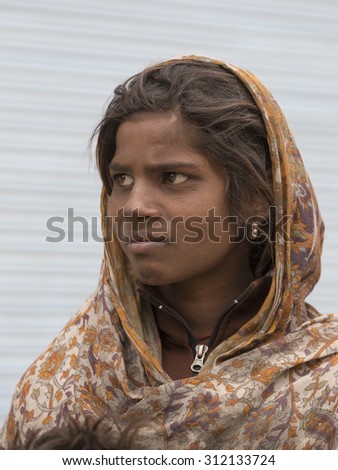 LEH, INDIA - JUNE 24, 2015: Unknown poor girl begs for money from a passerby on the street in Leh, Ladakh. Poverty is a major issue in India