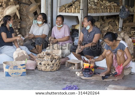 UBUD, BALI, INDONESIA - MARCH 23, 2015 : Unidentified women are making wooden souvenirs for tourists. Woodcarving is a traditional handicraft in Bali