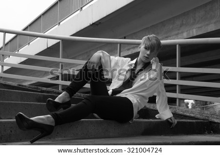 Young woman model in manly style wearing tie sit on stairs.