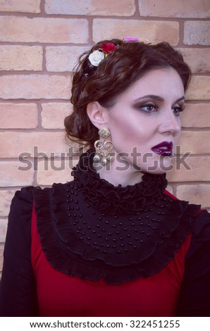 Portrait of beautiful young woman in baroque style near brick wall.