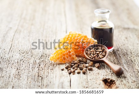Propolis tincture with honeycomb on old wooden background
