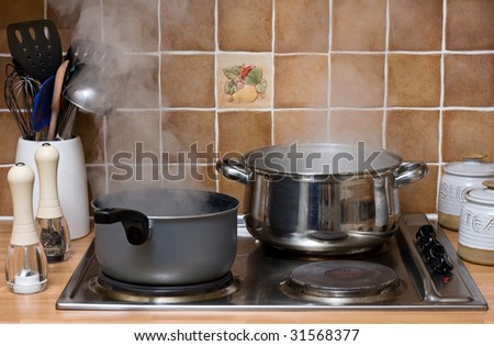 Pans of water boiling on an electric hob in a kitchen
