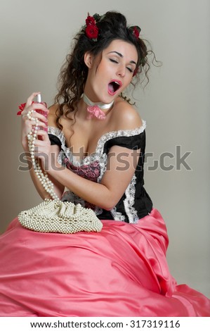 beautiful young woman dressed in vintage style with a bottle of with a bottle of perfume and pearl beads