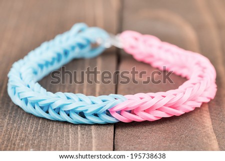 Slightly desaturated, two color, rubber bracelet over a wooden background