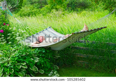 A man sleeping in his hammock on a hot summer day, with a ruby throated hummingbird perched, watching him.