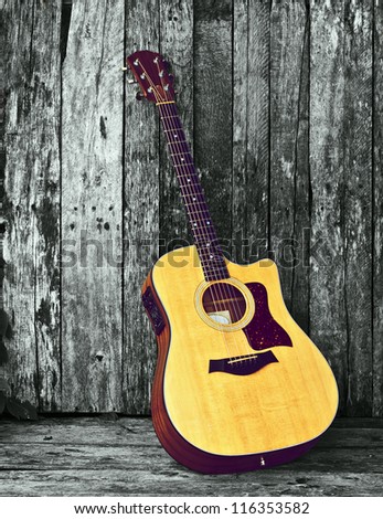 Acoustic guitar on a grunge wood  desaturated backdrop with copy space.