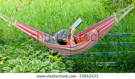 People. Man in hammock with dog working on laptop during summer holidays.