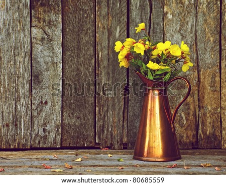 Evening primrose flowers in an antique copper vase on a rustic wood backdrop with copy space.