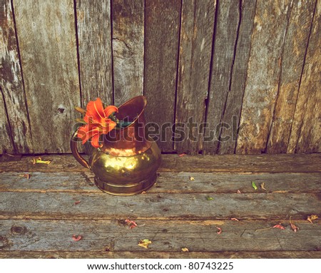 Lilly flower in an antique copper vase on a rustic wood backdrop with copy space.