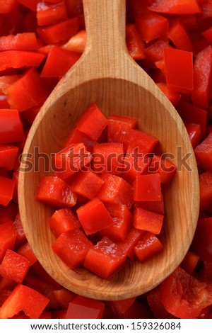 Top view of wooden spoon full of diced red bell pepper