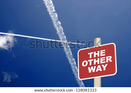The other way sign with jet trails crossing in a dark blue sky
