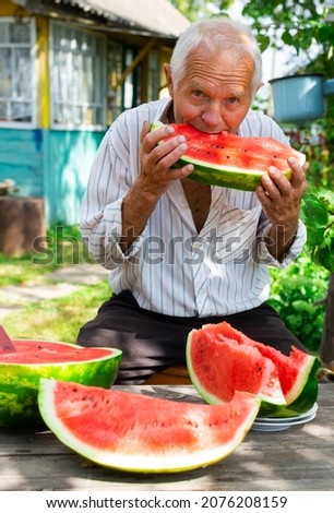 happy old señor takes a bite of watermelon in the garden of a country estate Foto stock © 