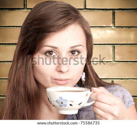 Beautiful brunette lady drinking bracing coffee over grunge brickwall