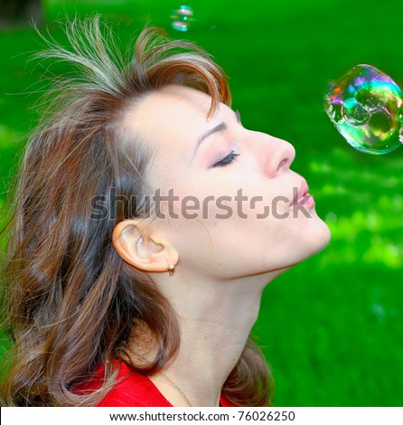 portrait of stunning girl inflating soap bubbles