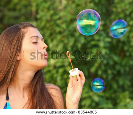 Young girl inflating colorful soap bubbles
