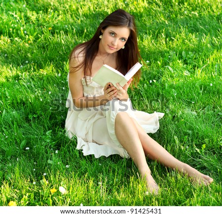 Young beautiful woman reading a book in nature