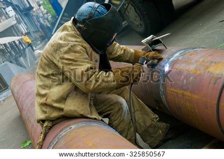 ODESSA, UKRAINE - 09 October 2015: Welder welds pipe segments. Repair and replacement of outdated pipes in the city center.