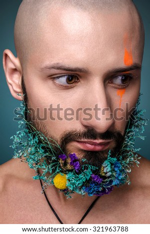 Man with creative makeup and flowers in his beard