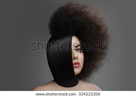 Beautiful brunette .  Fashion Model. Professional Makeup. shiny highlighter on skin, sexy gloss lips  hair smooth and laid his neck the other half curly stranded on  gray background