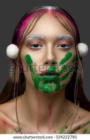Beautiful Young Woman with Clean Fresh Skin. Close up Portrait. Fashion Perfect Skin. Professional pink Makeup. Fashion shiny highlighter on skin, sexy gloss lips, white eyebrows, green hand print