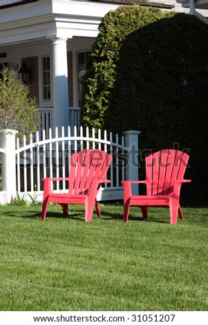 Two red lawn chairs on the front lawn