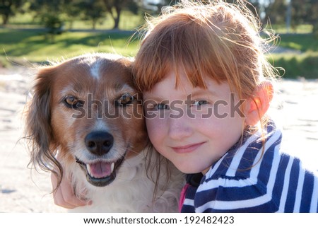 Red headed little girl hugging her red haired pet dog