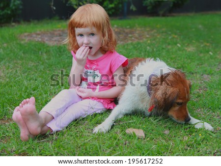 red headed girl with red haired dog eating dog biscuits