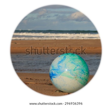 color concept image for global environmental issue using inflatable rubber ball with earth like markings against ocean beach background shaped format