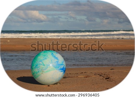 color concept image for global environmental issue using inflatable rubber ball with earth like markings against ocean beach background shaped format