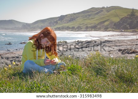 little red haired girl making daisy chains out of spring flowers - yellow oxalis weed flowers, at Pouawa Beach, Gisborne, East Coast, North Island, New Zealand