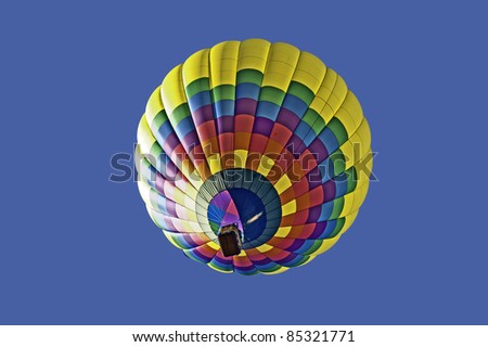 Colorful hot air balloon floats in a clear blue sky.