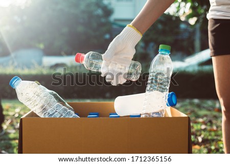 Volunteer woman keep plastic bottle into paper box at public park,Dispose recycle and waste management concept,Good conscious mind
