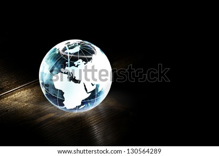 Blue glass earth globe on a wooden table with light