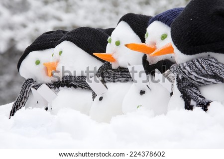 Line of snowmen with carol singing books, hats and scarfs in the snow for winter