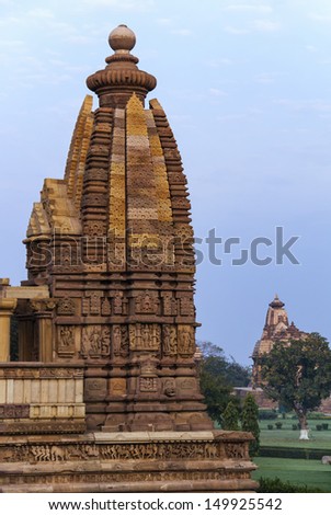Side dome of Hindu temple at Western site in India's Khajuraho isolated against early  morning skies. Over decorated oval dome tower turned deep warm reddish brown by early morning sun.
